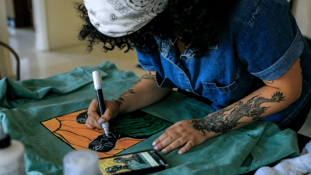 A person sitting at a table painting on a piece of fabric