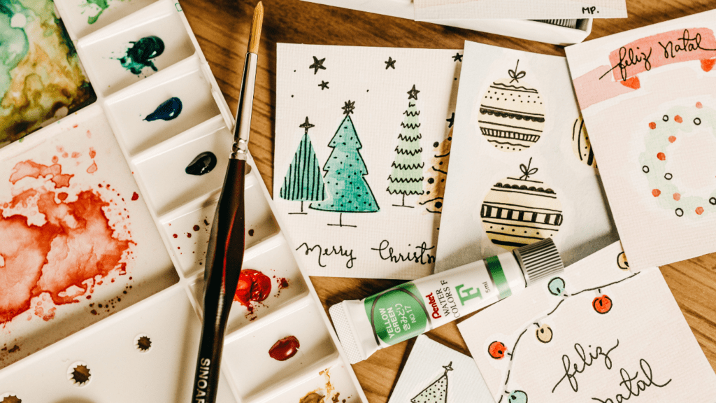 christmas cards are laid out on a table with paintbrushes and watercolors