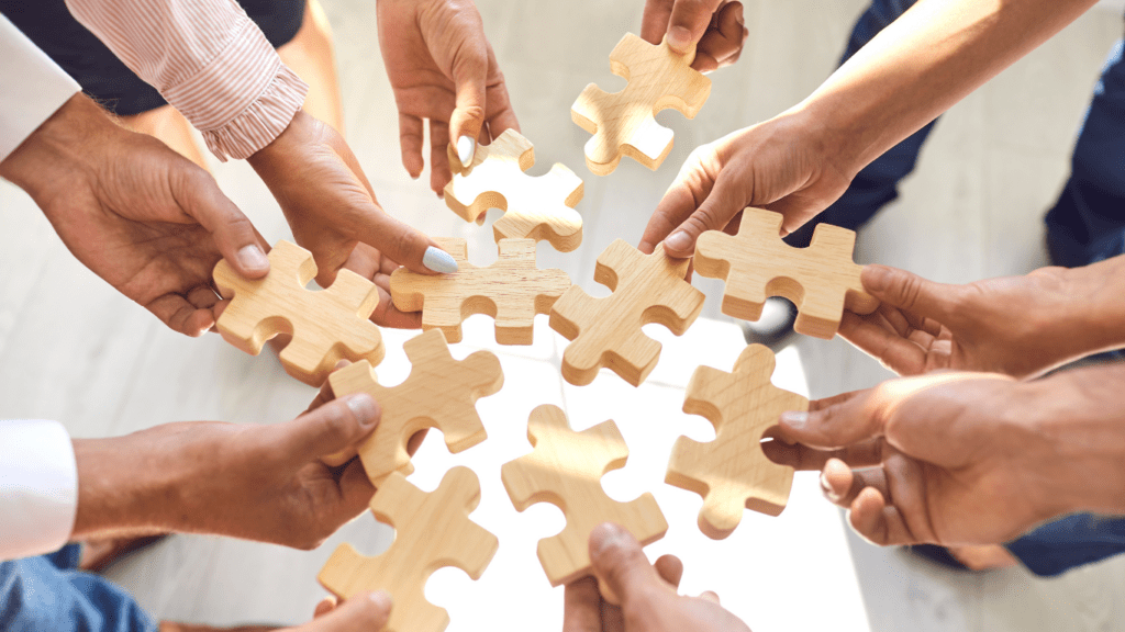 a group of people holding wooden puzzle pieces together