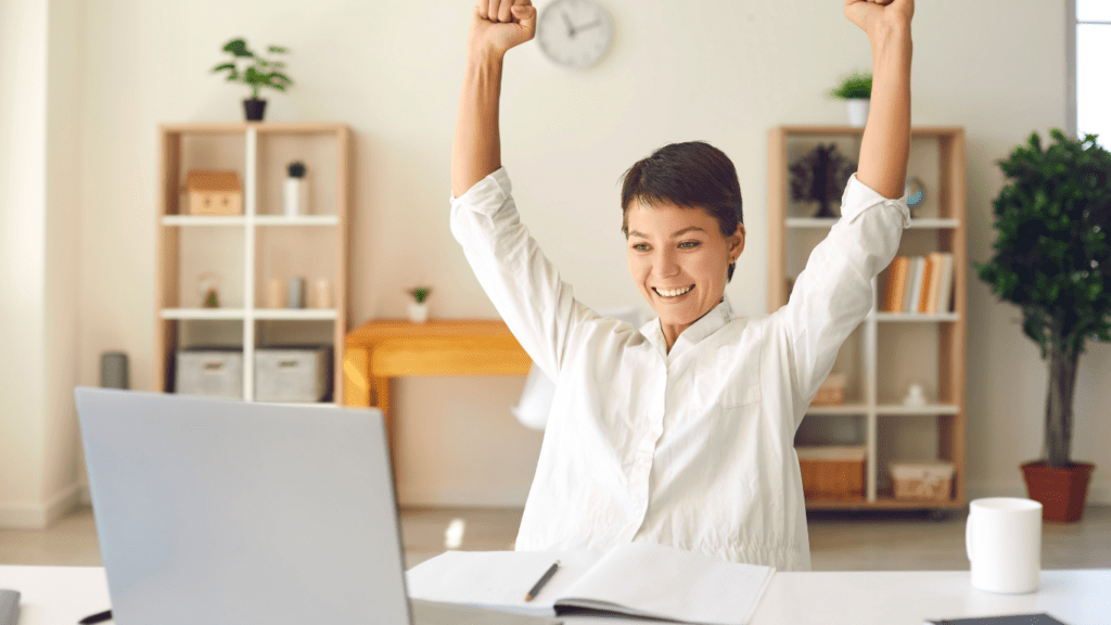 a person is sitting at their desk with their arms up in the air