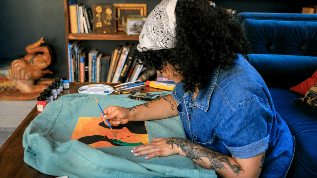 A person sitting at a table painting on a piece of fabric