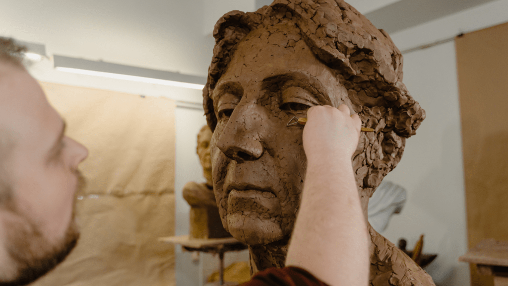 a person is working on a clay sculpture of a person