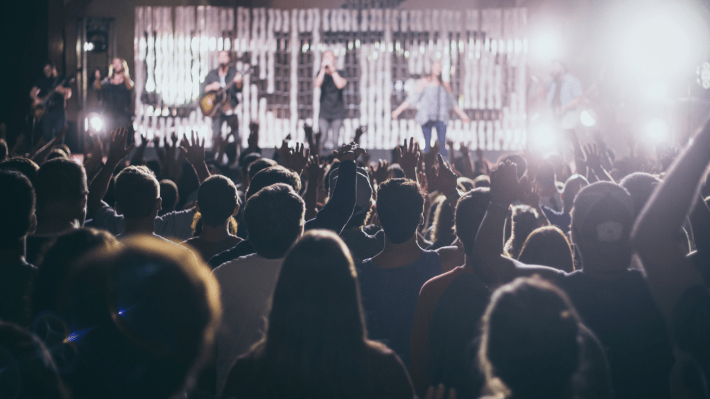 a crowd of people at a concert with their hands up in the air