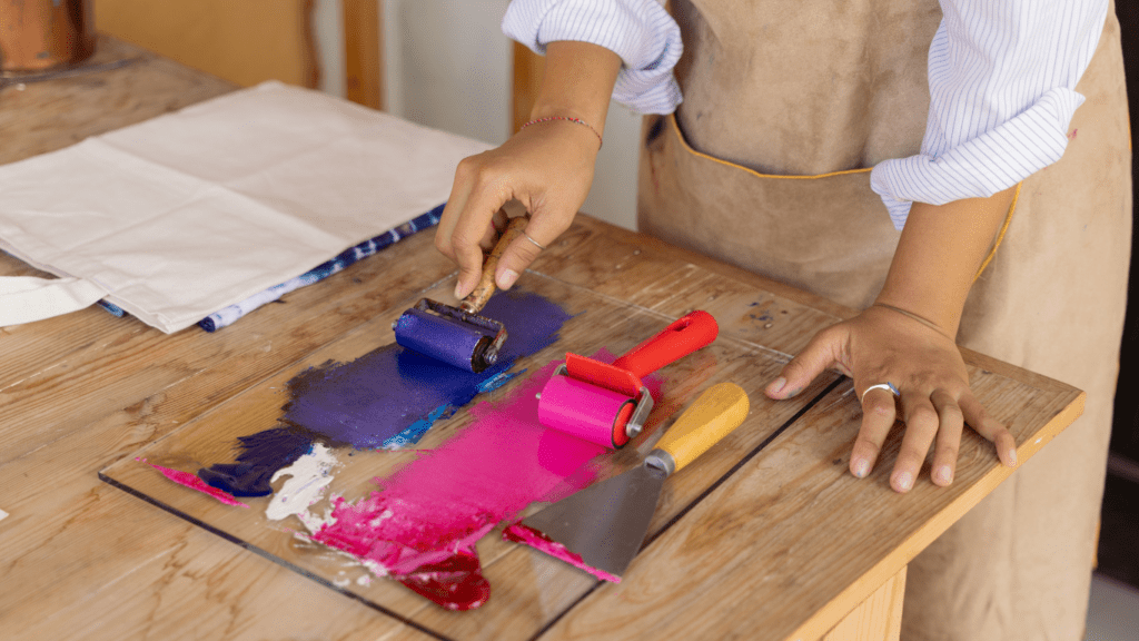 a person in an apron is using a roller to roll paint onto a piece of paper