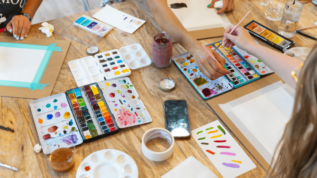 a group of people sitting around a table painting