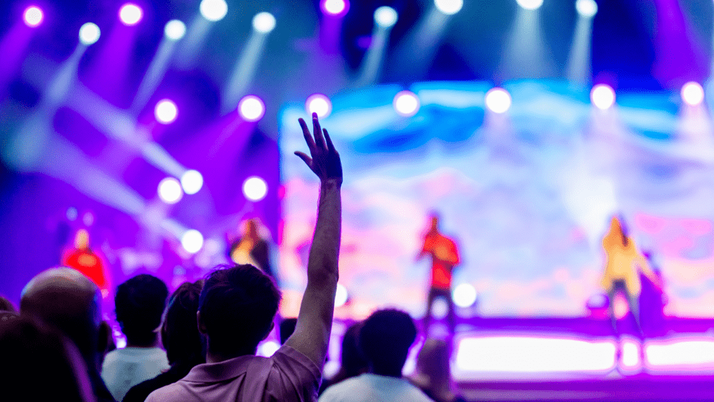 a crowd of people at a concert with their hands up in the air