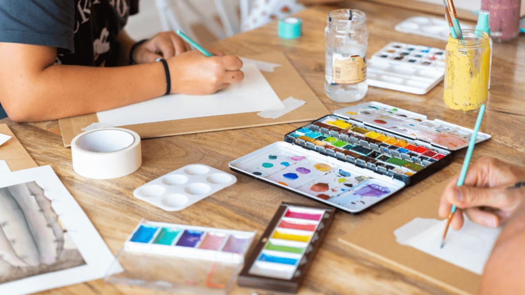 a group of people sitting around a table painting