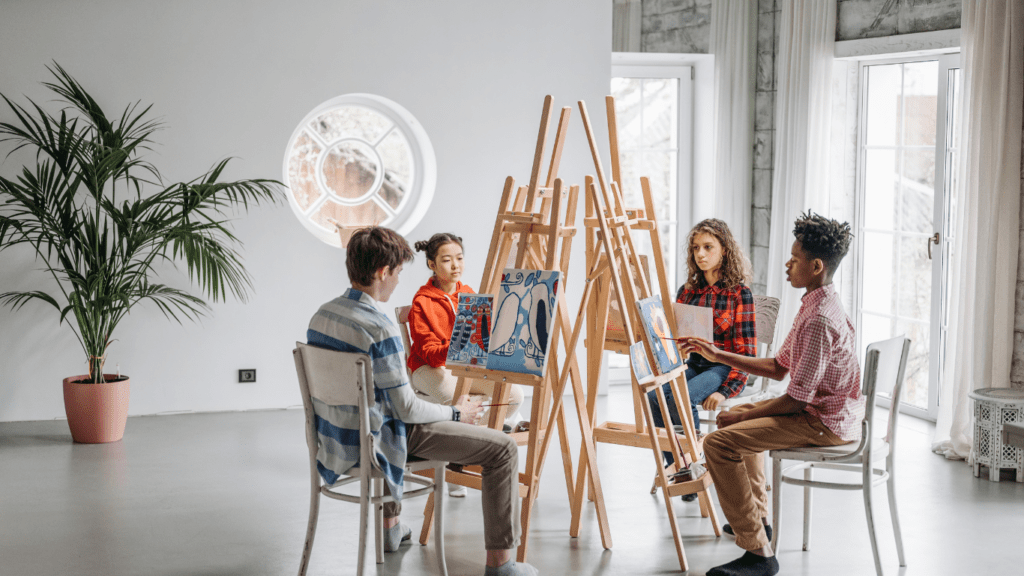 a group of people sitting on chairs and painting on easels