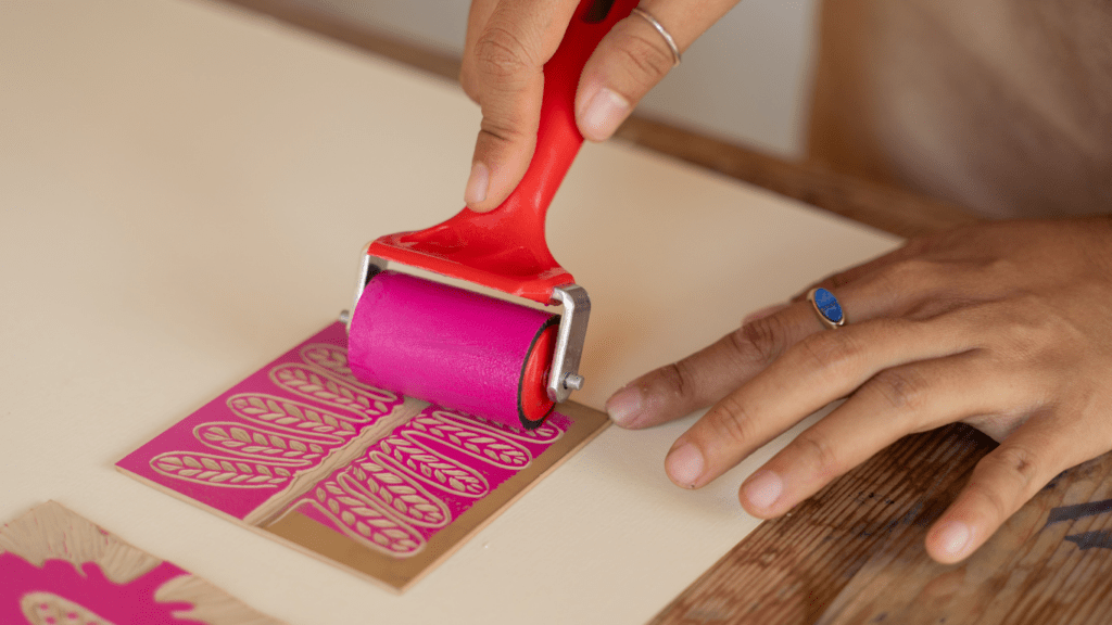 a person in an apron is using a roller to roll paint onto a piece of paper