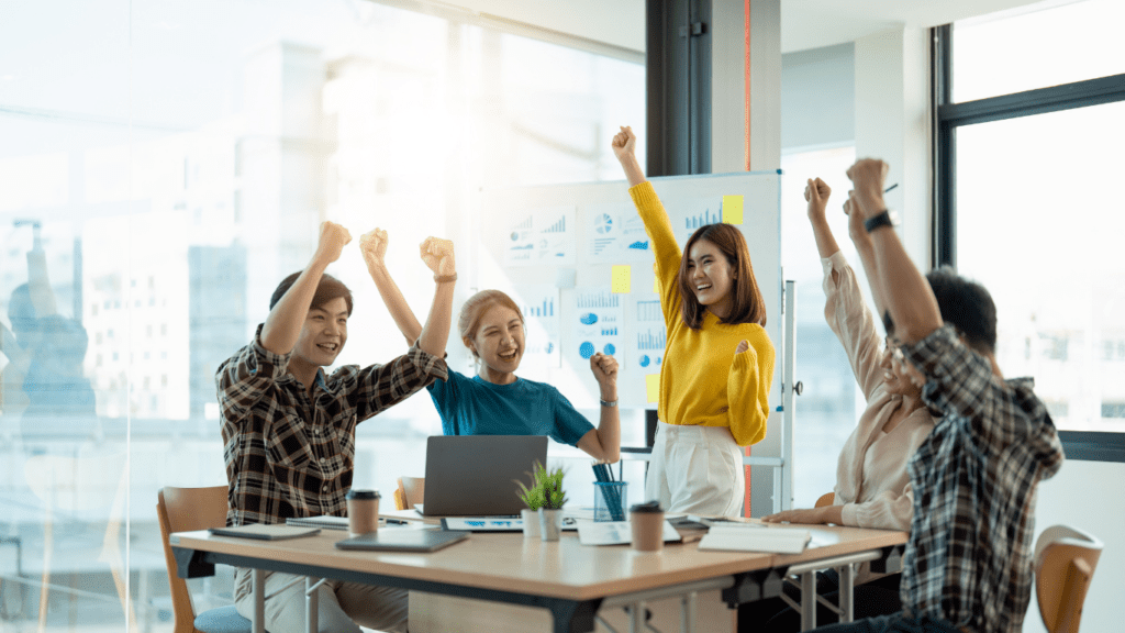 a person is sitting at their desk with their arms up in the air