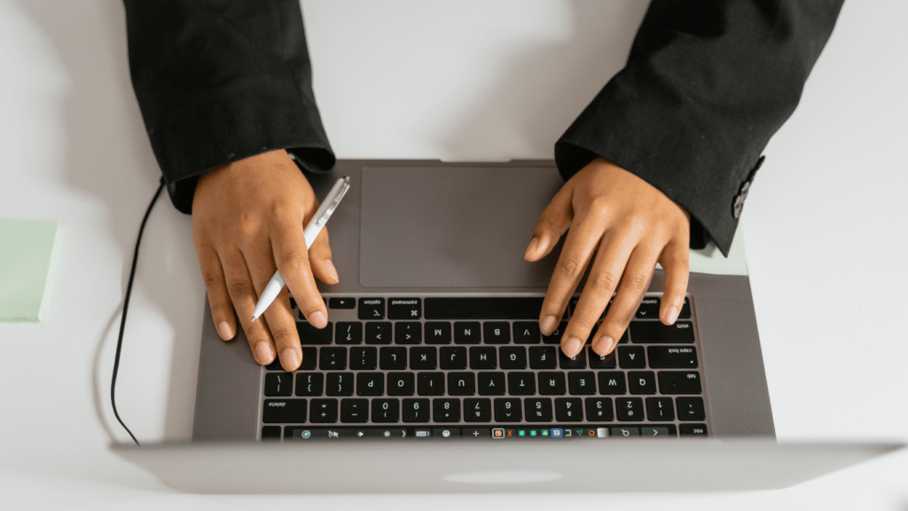 a person is working on a laptop with a pen in their hand