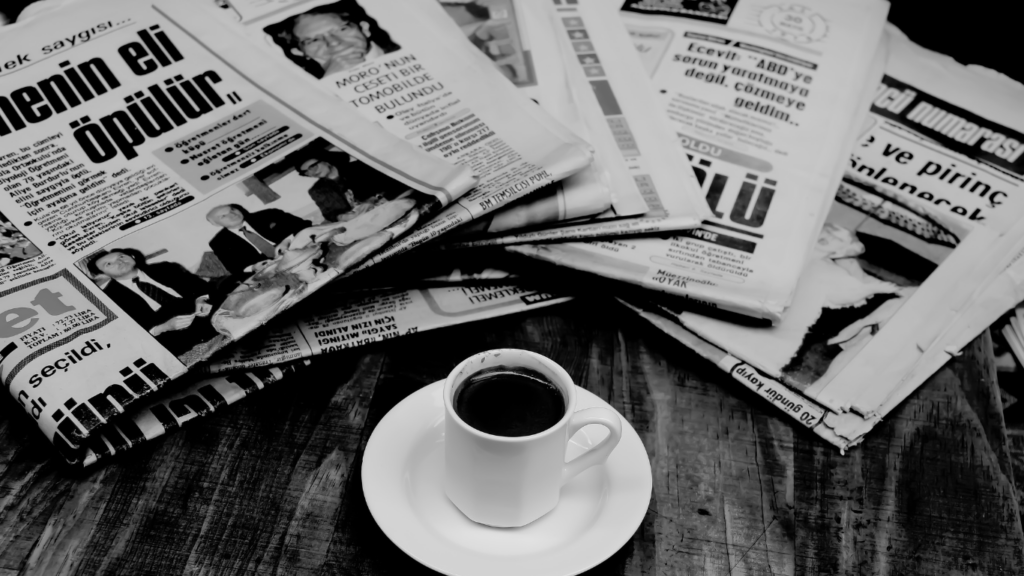 a stack of newspapers sitting on top of a wooden table